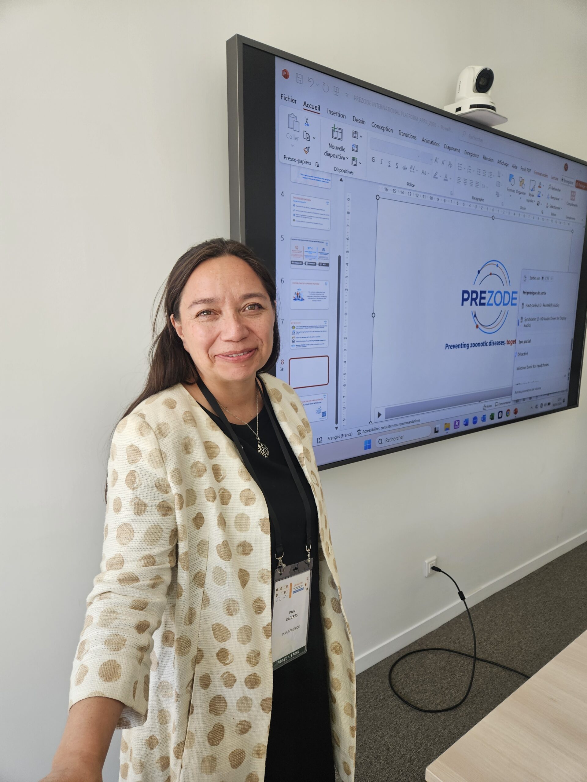 paula Caceres posing in front of a screen displaying her presentataion